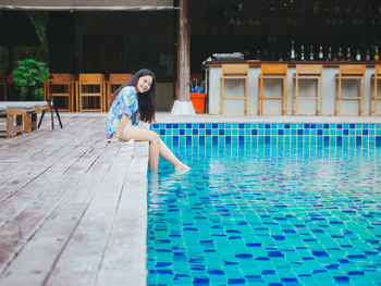 Young asian woman relaxing outdoor beside swimming pool in hotel resort for leisure vacation