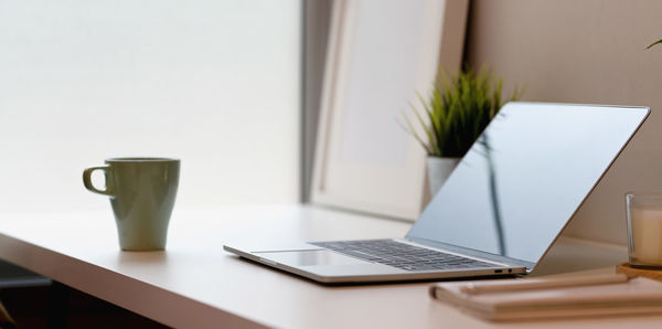 Laptop with mug on table at home