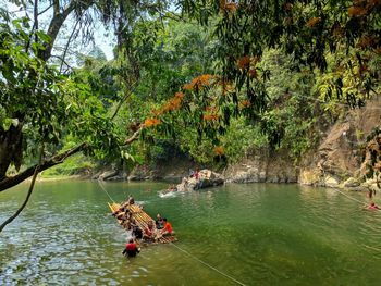 People on boat in river against trees