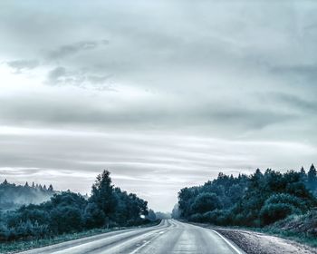 Road by trees against sky