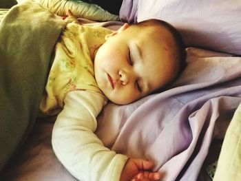 Close-up of baby sleeping on bed at home