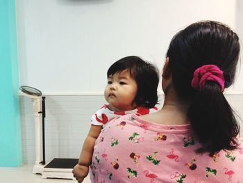 Rear view of mother carrying cute daughter