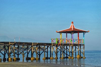 Gazebo on pier by sea against clear sky