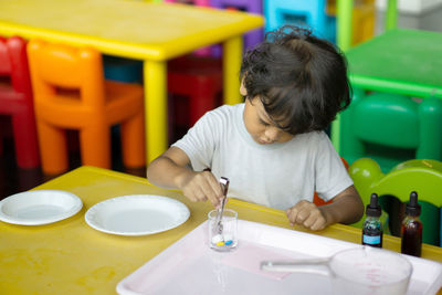 Boy holding dropper while painting toy