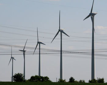 Low angle view of wind turbines against sky