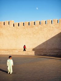 People standing on sand against clear sky