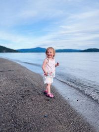 Full length of girl running on beach against sky