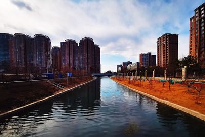 River by buildings in city against sky
