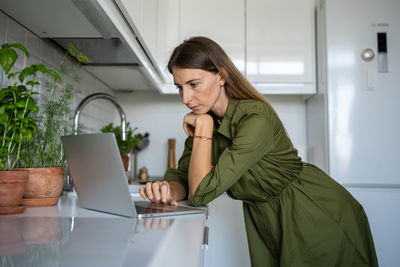 Focused female engrossed in reading of cooking receipts, choosing food, products in online shop