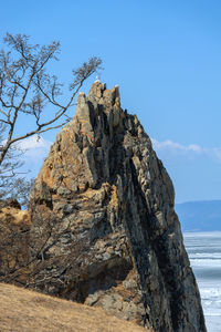 Rock formation in sea against sky