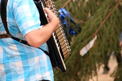 Midsection of man playing accordion while standing outdoors