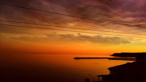 Scenic view of sea against cloudy sky at sunset