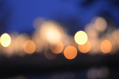 Defocused image of illuminated lights against sky at night