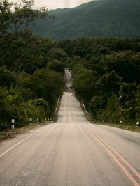 Empty road amidst trees against sky