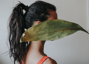 Rear view of young woman holding leaf