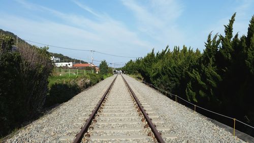 Railroad tracks against cloudy sky