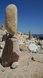 Rock formation by sea against clear blue sky