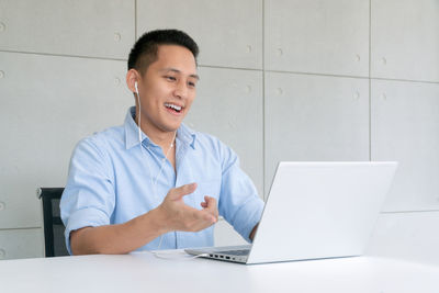 Smiling man using laptop while sitting on table