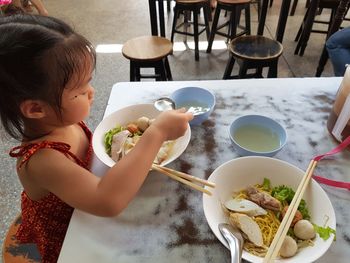 High angle view of girl holding food on table