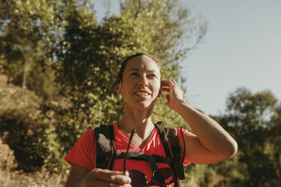 Portrait of smiling woman holding umbrella against trees