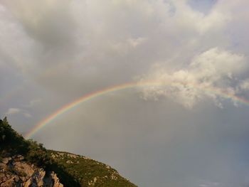 Scenic view of rainbow over mountains against sky