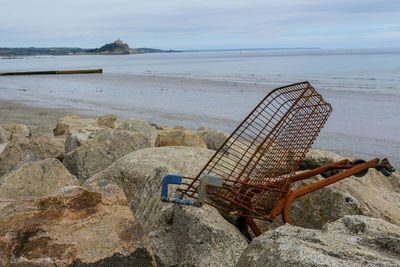 Abandoned shopping cart amidst rocks at beach