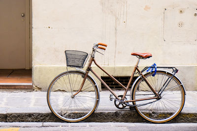 Bicycle on sidewalk against wall