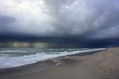 Scenic view of beach against cloudy sky
