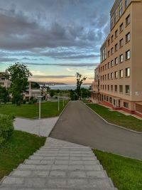 Road amidst buildings against sky during sunset