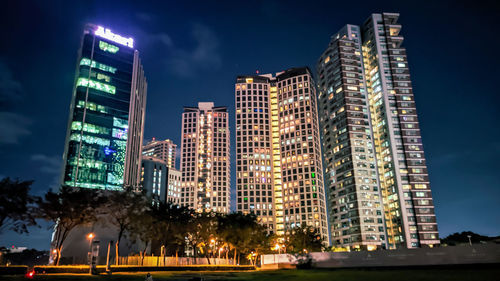 Low angle view of illuminated buildings against sky at night