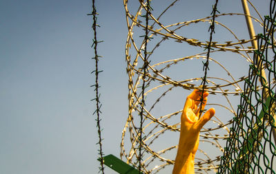 Low angle view of barbed wire fence against sky