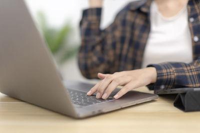 Midsection of woman using laptop on table