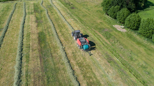Black tractor with a red straw chamber press during the straw harvest on a mown field