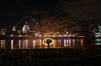 Man performing wire wool against st pauls cathedral at night
