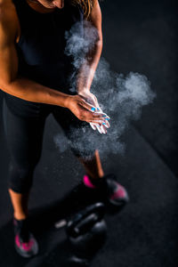 Athlete applying powder on hand while standing by weights