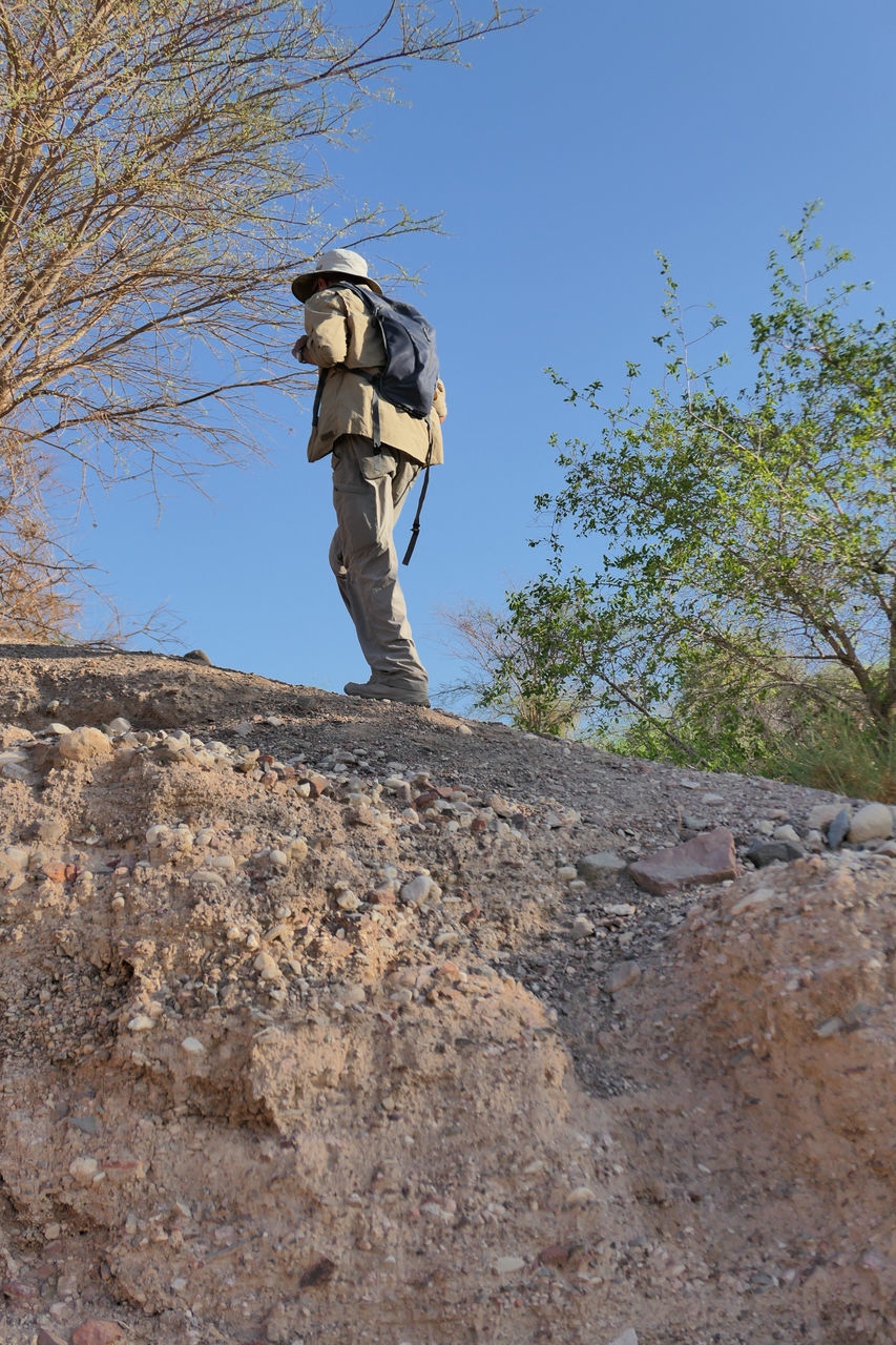 LOW ANGLE VIEW OF MAN STANDING ON ROCK