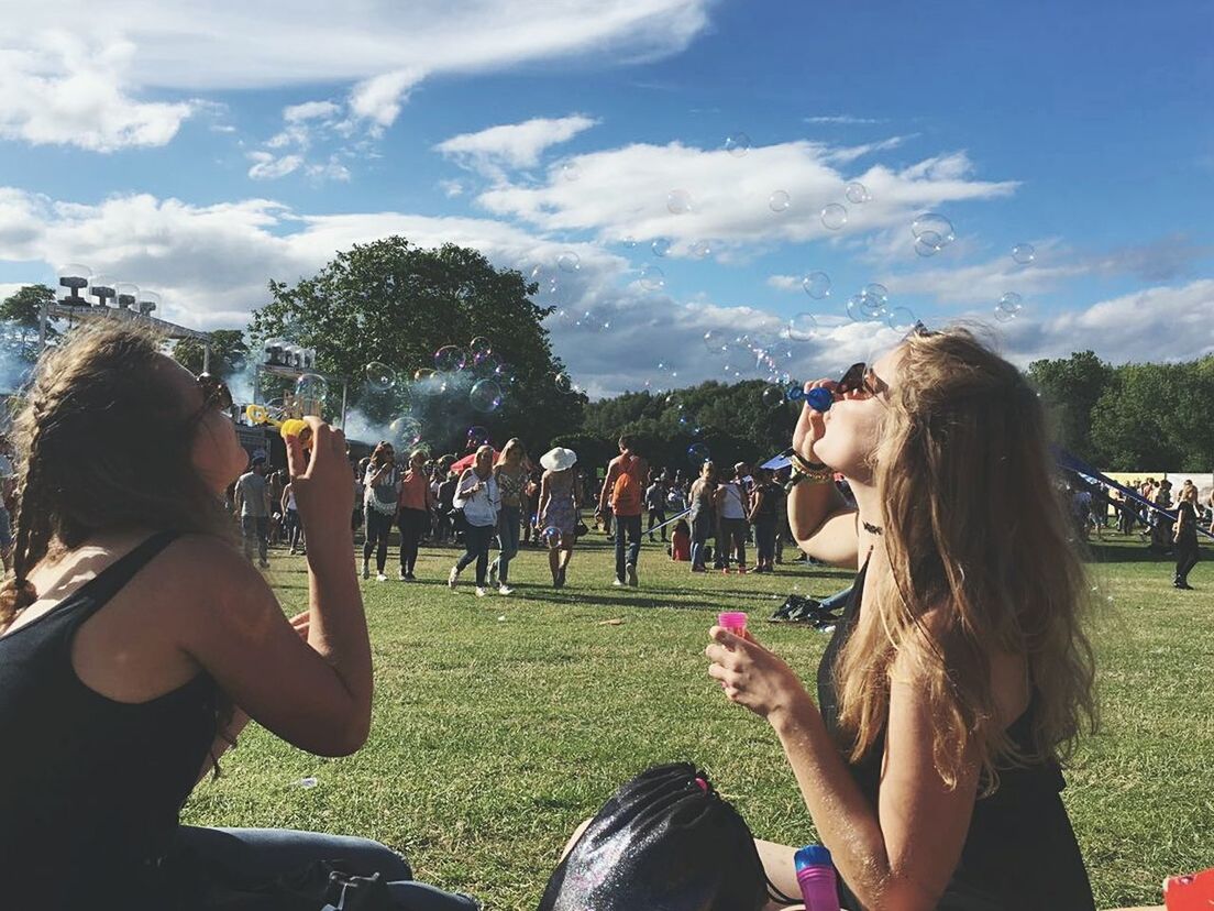 real people, leisure activity, sky, large group of people, day, cloud - sky, drinking, outdoors, tree, grass, togetherness, lifestyles, women, photographing, men, sitting, young adult, young women, bubble wand, nature, crowd, adult, people