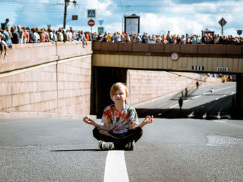 Full length of woman sitting on road in city