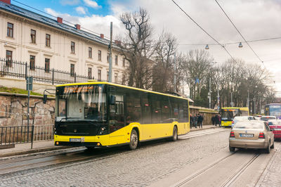 Vehicles on road by railroad tracks against sky in city