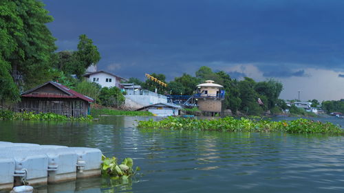 Houses by lake and buildings against sky