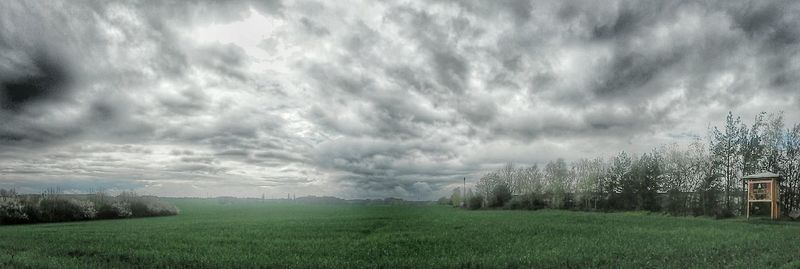 Scenic view of grassy field against cloudy sky