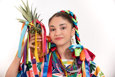 Portrait of young woman holding multi colored pencils against white background