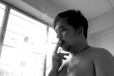 Portrait of young man smoking at home