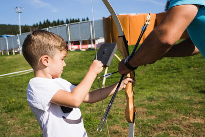 Coach giving archery training to boy outdoor