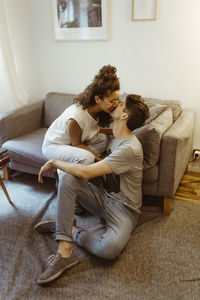 Romantic boyfriend and girlfriend kissing each other sitting in living room at home