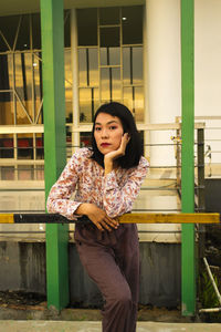 Portrait of smiling young woman standing against built structure