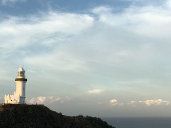 Lighthouse by sea against sky