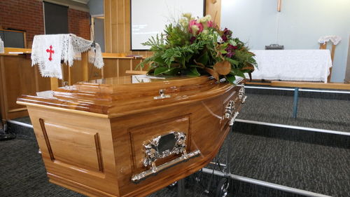 Closeup shot of a funeral casket or coffin in a hearse or chapel or burial at cemetery
