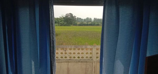 Scenic view of field seen through window