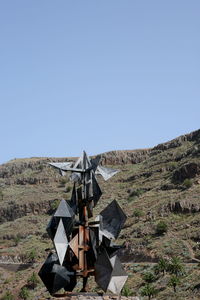 Windmill on field against clear blue sky